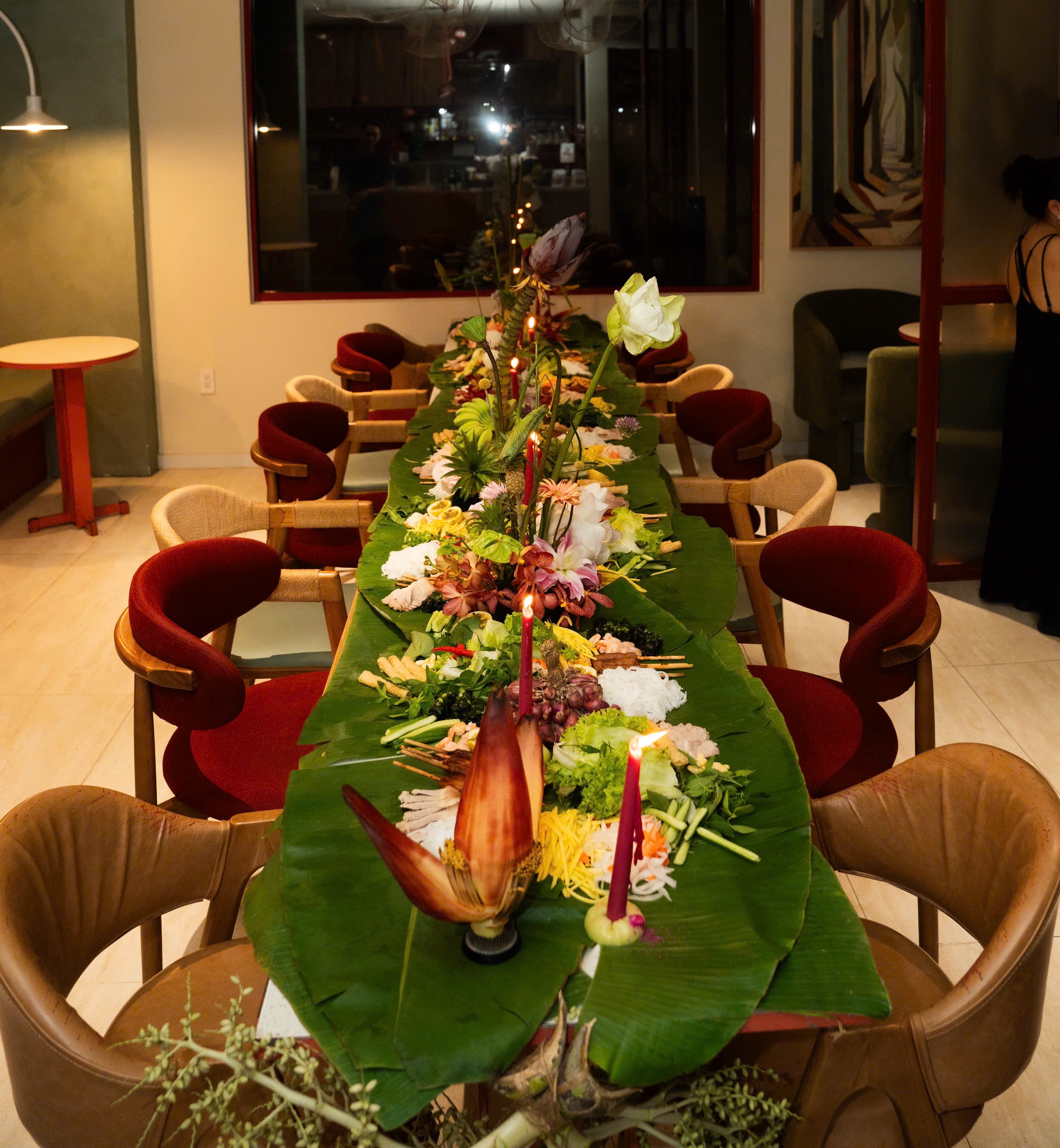 Long table set with tropical florals, banana blossom and lotus among Vietnamese dishes